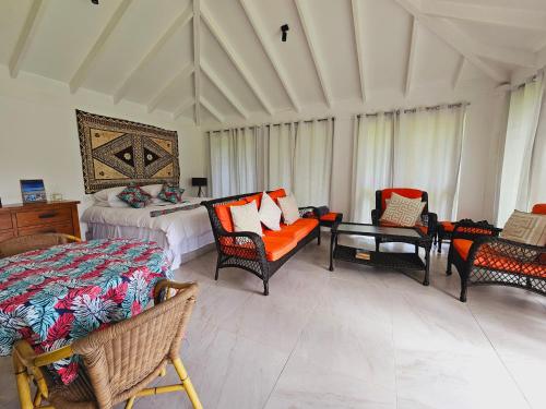 ein Schlafzimmer mit einem Bett, Stühlen und einem Tisch in der Unterkunft The Estate Cottage in Savusavu