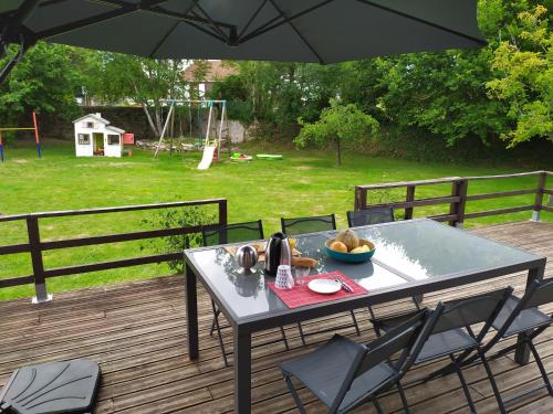 une table et des chaises sur une terrasse avec un parasol dans l'établissement Chalet Gîte Belle Ile en Lormes, à Lormes