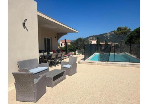 une terrasse avec des chaises en osier et une piscine dans l'établissement Pascaloux, à Lumio