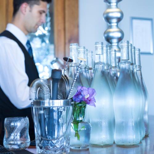 a man sitting at a table with glass bottles at Somerville Hotel in Saint Aubin