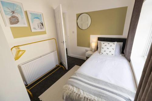 a small bedroom with a bed and a mirror at Charming House - 3 minute's walk to the beach - Free Parking, Smart TV and Fast Wifi by Yoko Property in Redcar