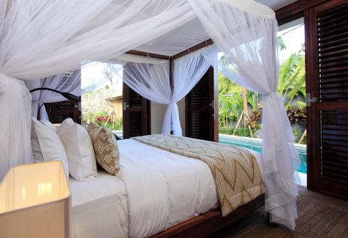 a bedroom with a bed with a canopy and a pool at Villa Suar Drupadi in Seminyak