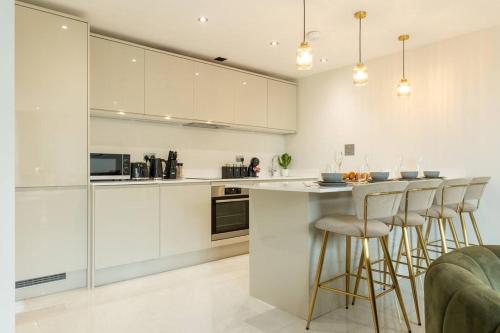 a kitchen with white cabinets and a bar with stools at Elegant City Centre Apartment 2 Bedroom With Free Parking in Cardiff