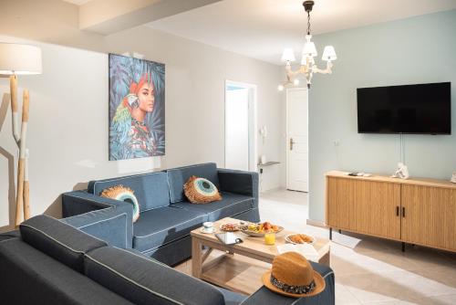 a living room with a blue couch and a tv at Ammos Lux Apartments in Agia Triada