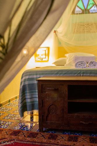 a bedroom with a bed and a wooden table at Riad Des Plages in Bouznika