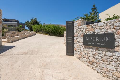 a sign for the entrance to a resort with a stone wall at Imperium Luxury Villas-Sauna, Jacuzzi, Heated Pool & Gym-Chania in Kato Galatas