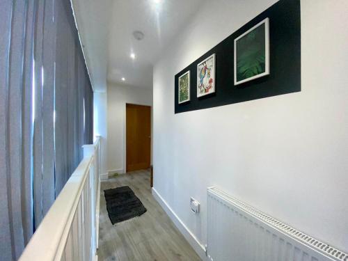 a hallway with a white wall with two pictures on it at Apartment 1 in Manchester