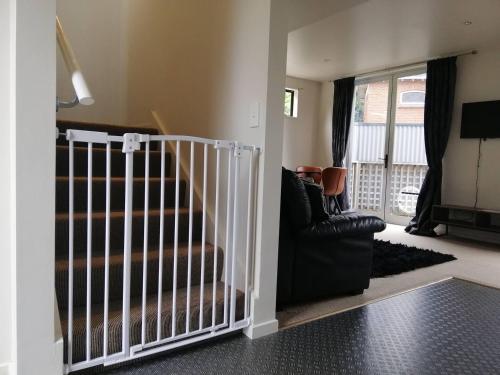 a living room with a staircase and a couch at A Stones Throw From Town A-frame in Dunedin