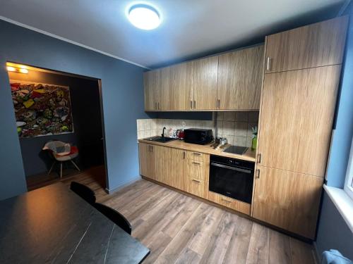 a small kitchen with wooden cabinets and a table at White Neverland in Jelgava