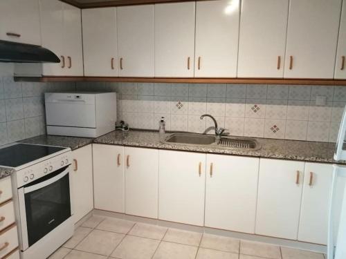 a kitchen with white cabinets and a sink at Nansy's house in Áyios Pávlos