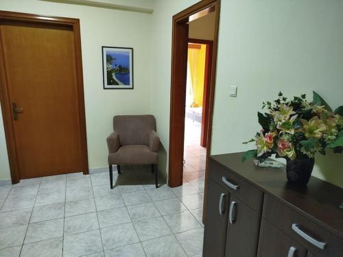 a living room with a chair and a vase of flowers at Nansy's house in Áyios Pávlos