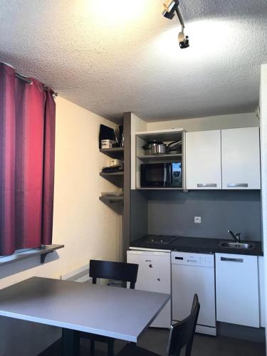 une cuisine avec une table et des chaises dans une pièce dans l'établissement Résidence Les Choucas - Studio rénové, pied des pistes MAE-9004, à Aime La Plagne