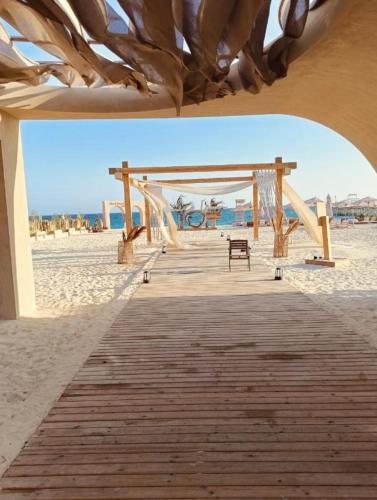 a wooden boardwalk on the beach with a bench at Luxury Twin Villa in Mountain View Ras Elhikma in Ras Elhekma