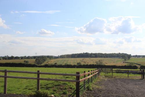a wooden fence in a field with green grass at Parkfields Barns Self Catering Accommodation in Buckingham