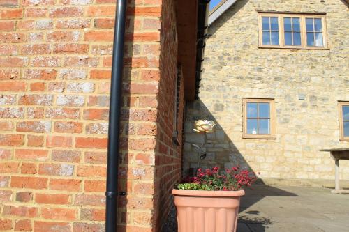 a pot of flowers in front of a brick building at Parkfields Barns Self Catering Accommodation in Buckingham