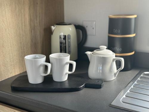 a counter with three coffee cups and a coffee pot at Eden Holiday Home in Whitley Bay