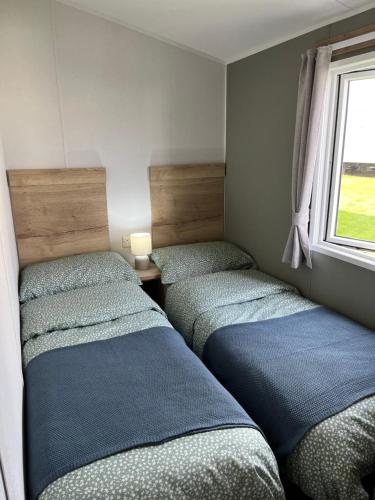 ウィットリー・ベイにあるEden Holiday Homeの窓のある部屋にベッドが3つある