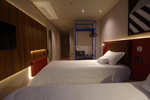 a hotel room with two beds and a television at Golden Tower Express Nações Unidas by Fênix Hotéis in Sao Paulo