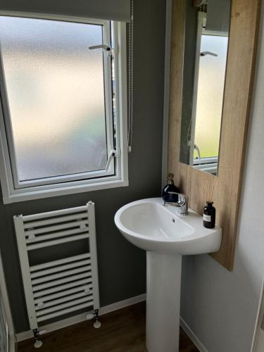 ウィットリー・ベイにあるEden Holiday Homeの洗面台と鏡と窓のあるバスルーム