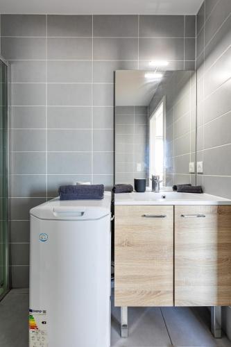 La salle de bains est pourvue d'un réfrigérateur blanc et d'un miroir. dans l'établissement Appartement cosy Place des Halles - Hyper centre, à Strasbourg