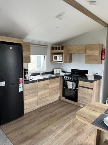 a kitchen with wooden cabinets and a black refrigerator at Eden Holiday Home in Whitley Bay