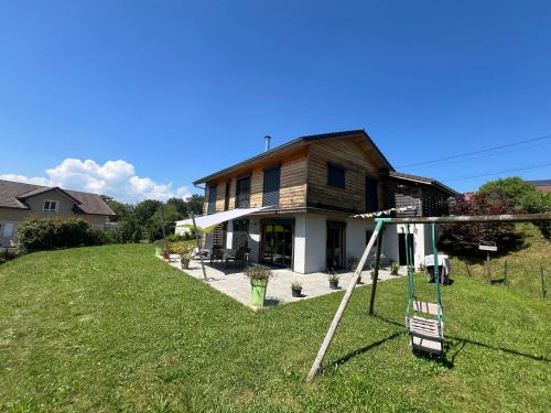une maison avec une balançoire dans la cour dans l'établissement L écrin verdoyant, à Jonzier-Épagny