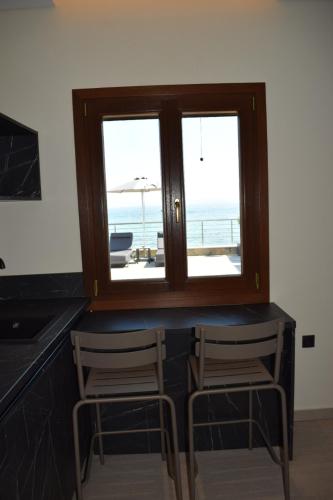 a kitchen with two chairs and a window with a view of the ocean at La vie luxury suites in Megalochori