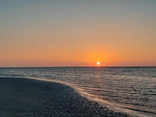 a sunset over the ocean with a sandy beach at Friesenrose Süd in Spiekeroog
