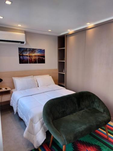 a bedroom with a large bed and a green chair at Studio Giovanni Gronchi - Ao Lado do Metrô in São Paulo