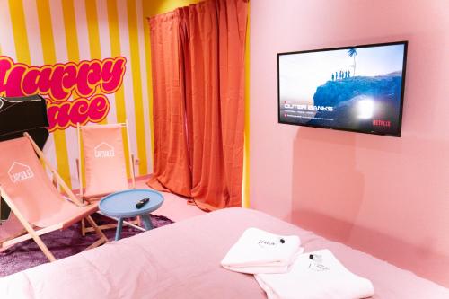 a room with a tv and a bed and a chair at Capsule Girl Power SPA - balneo - Sauna - Karaoké - Billard - 2 chambres in Charleroi