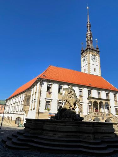 a building with a clock tower with a statue in front of it at Chata Olomouc Tovéř in Tovéř