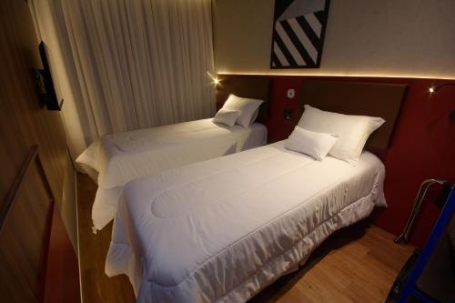 two beds in a hotel room with white sheets at Golden Tower Express Nações Unidas by Fênix Hotéis in Sao Paulo