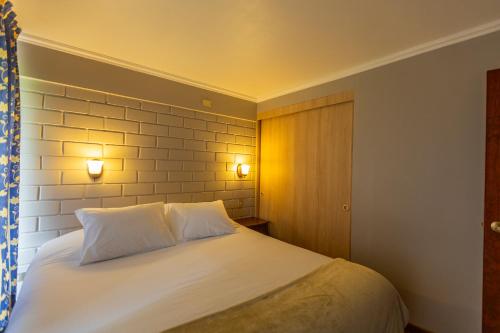 a bedroom with a white bed with two pillows at Apart Hotel La Herradura - Héroes Parques in Coquimbo