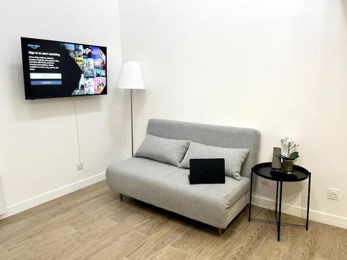 a living room with a couch and a tv on the wall at 734 Elégant studio en mezzanine proche du métro L9 in Bagnolet