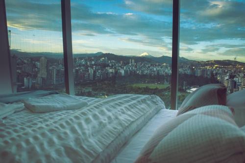 a bed in a room with a view of a city at Hermoso Penthouse Vistas Espectacular in Quito