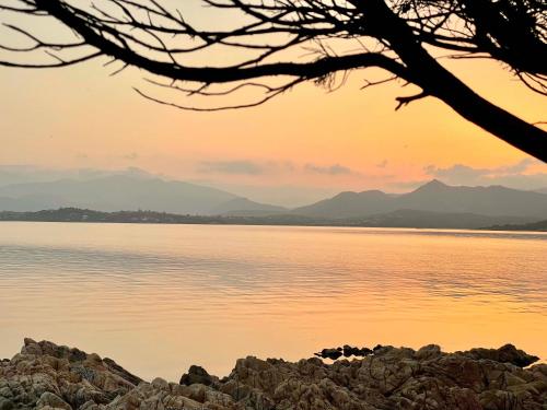 a sunset over the water with mountains in the background at Strepitoso 4 Camere da letto e Terrazza Vista Mare in Capo Coda Cavallo