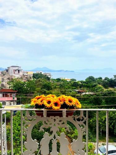 a vase filled with yellow flowers on a balcony at Casa Nina-Bacoli Elegant & View in Bacoli