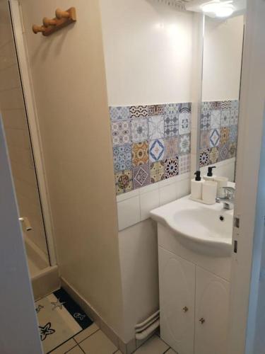 une salle de bain blanche avec un lavabo et un miroir dans l'établissement Studio jardin 300 m plage, à Carnac