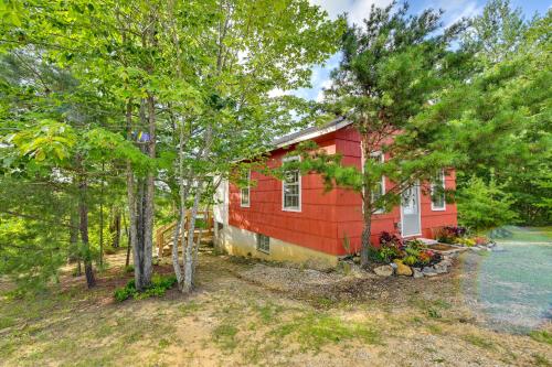 a red house with trees in front of it at Cozy Beattyville Cabin with Fire Pit and Hot Tub in Beattyville
