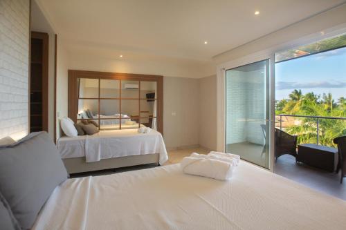 a bedroom with two beds and a balcony at Hotel Tango Suítes Cumbuco in Cumbuco
