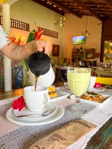 a person pouring coffee into a cup on a table at Pousada Rancho da Serra in Martins
