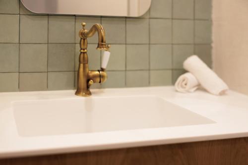 a bathroom sink with a faucet and a roll of toilet paper at Celestial Suites-TOP LOCATION in Corfu Town
