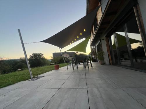 un patio avec une table et des chaises sous un parasol dans l'établissement L écrin verdoyant, à Jonzier-Épagny