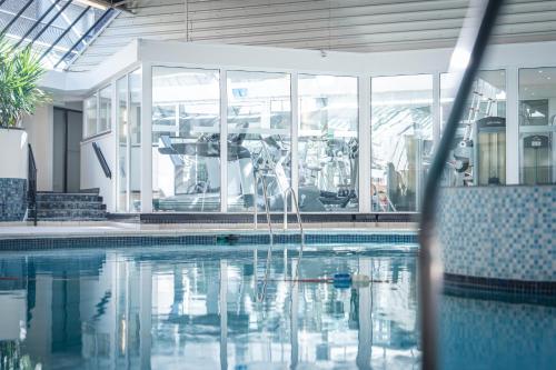 a swimming pool in a large building with glass windows at The Aberdeen Dyce Hotel in Dyce