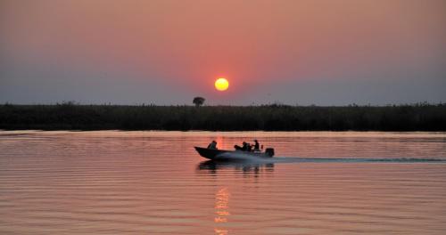 a group of people on a boat in the water at sunset at Cresta Mowana Safari Resort & Spa in Kasane