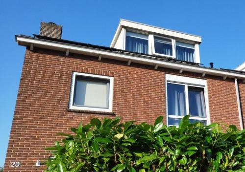 a red brick house with two windows and a hedge at Tranquil Retreat - Free American Pancake-Guest House in Arnhem