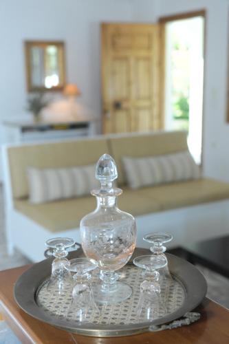 a glass bottle and two glasses on a tray on a table at Athena Villas Olive Grove & Estate in Gouves