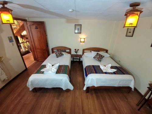 two beds in a room with wooden floors at Mía Leticia B&B in Quito
