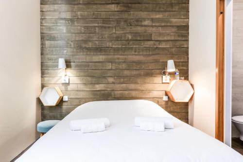 a bedroom with a white bed and a wooden wall at Logis Hôtel & Restaurant Le Cadet de Gascogne in Saint-Justin