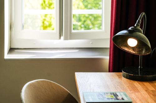 a lamp sitting on a table in front of a window at Logis Hôtel & Restaurant Le Cadet de Gascogne in Saint-Justin